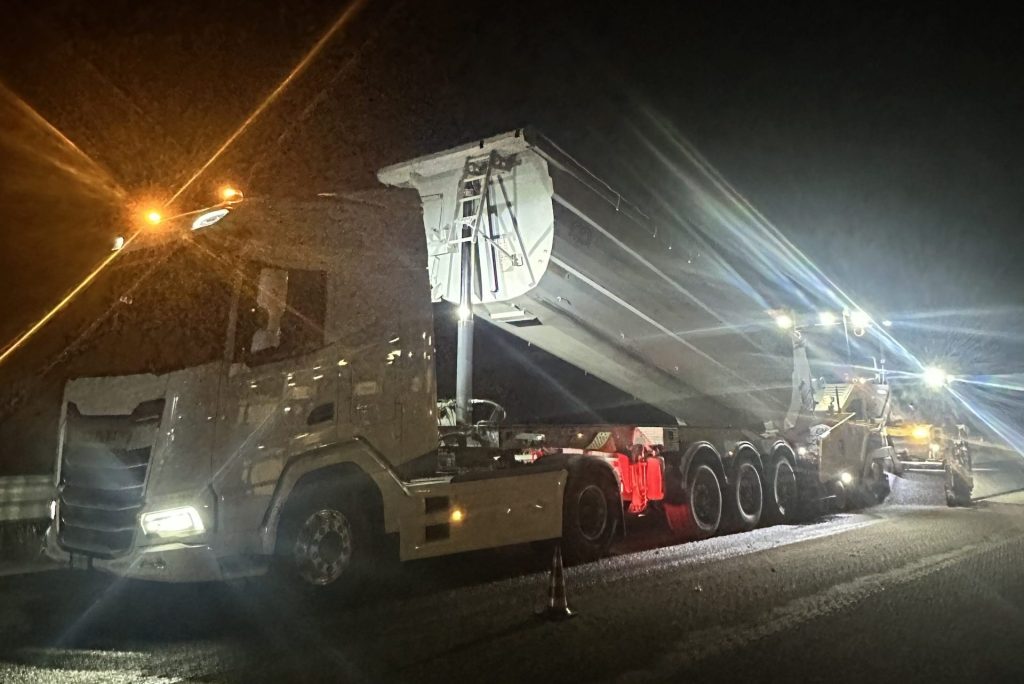Camion ribaltabile illuminato dai fari durante lavori stradali notturni