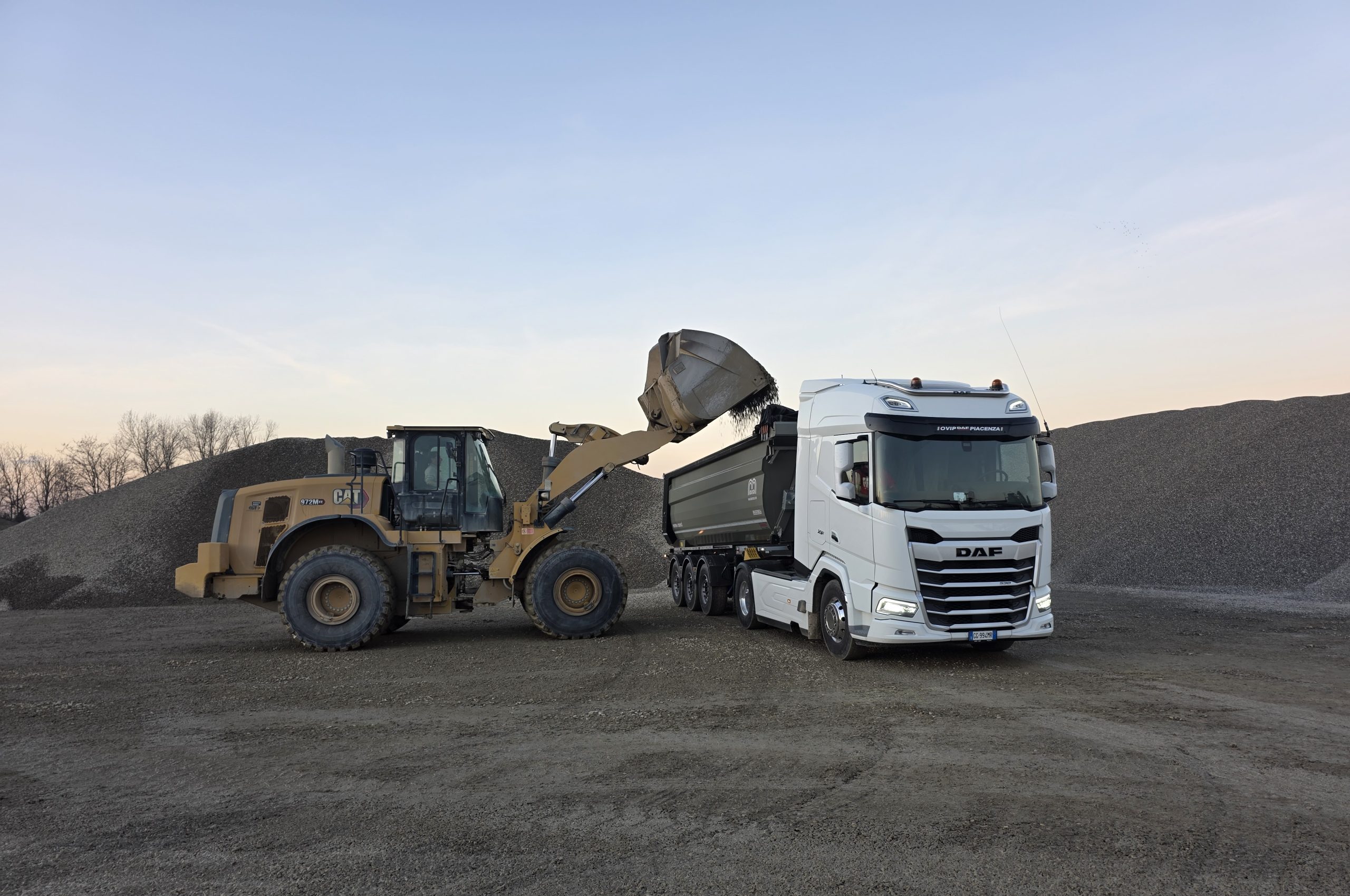 Pala gommata che carica ghiaia su un camion in cava
